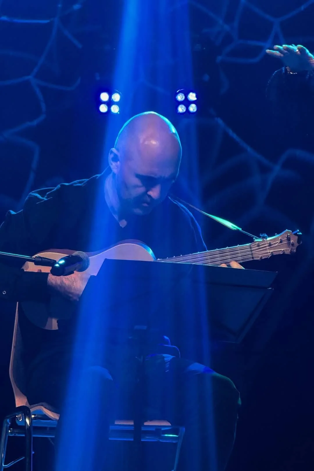 Maciej Kończak grający na gitarze renesansowej w niebieskim świetle scenicznym